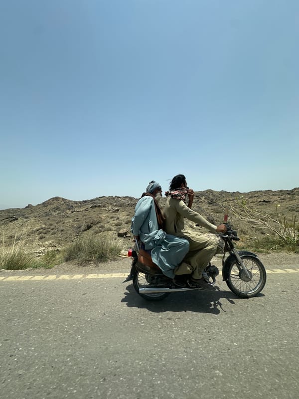 Motorcycle duo in traditional dress on a Pakistani road