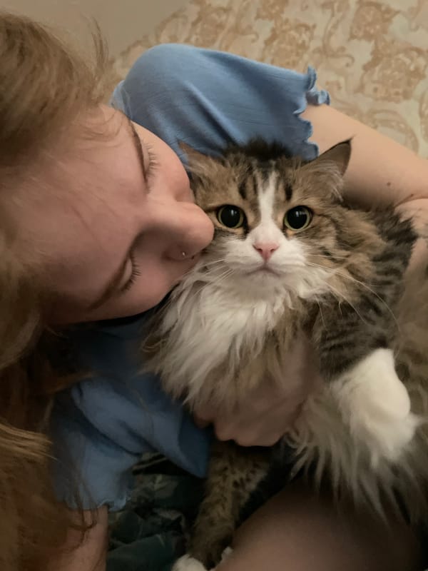 Woman rests with cat on chest in Izhevsk morning