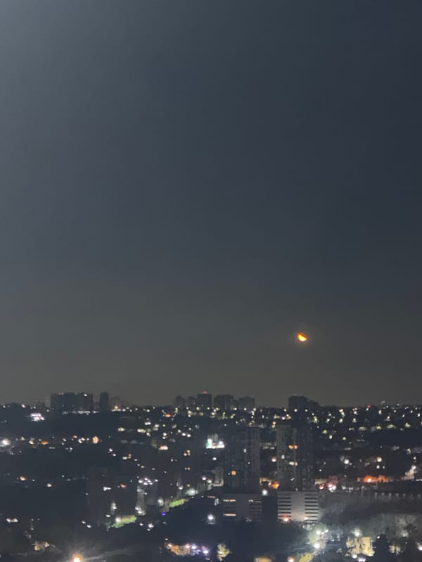 Crescent moon visible over illuminated Huixquilucan cityscape at night