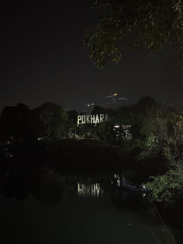 Illuminated POKHARA sign reflects in water at night