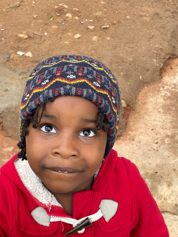 Child in red jacket photographed playing outdoors in Jos
