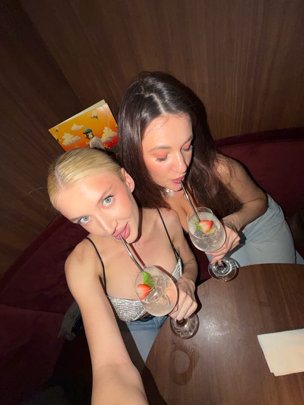 Two women share cocktails at wooden table