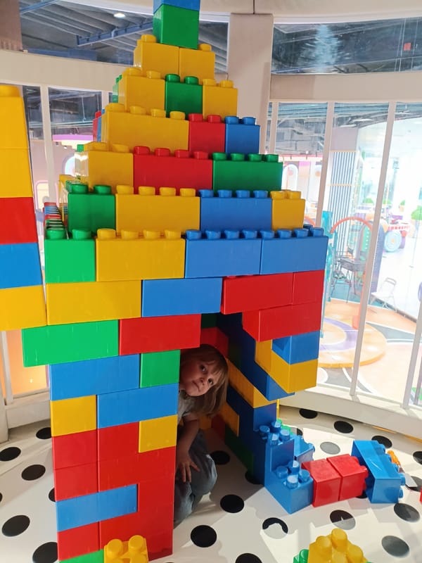 Child plays inside colorful oversized Lego brick structure