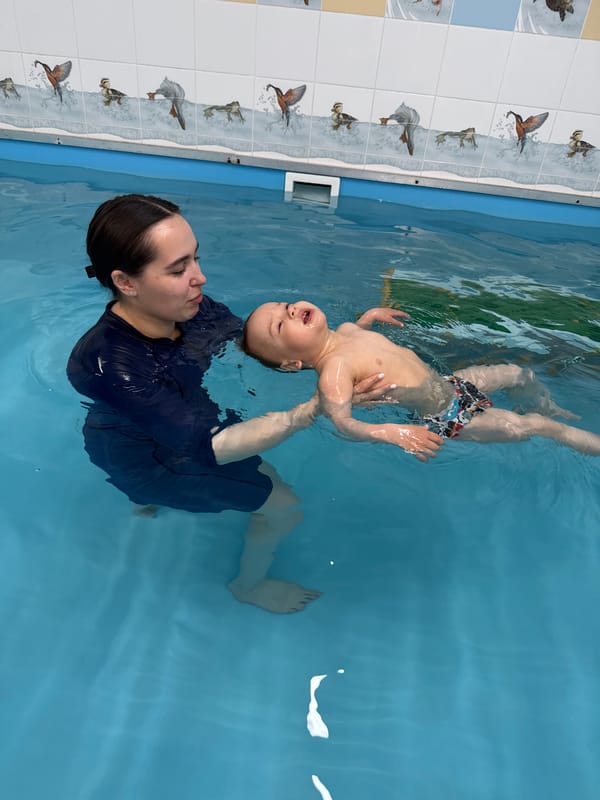 Woman holds child during swimming pool session