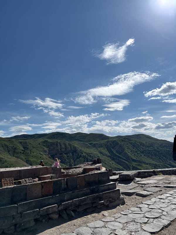 Tourist visits ancient Temple of Garni under partly cloudy skies