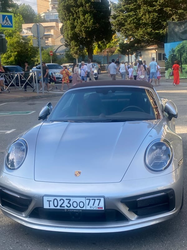 Toy vehicle rides and a parked Porsche in Sochi