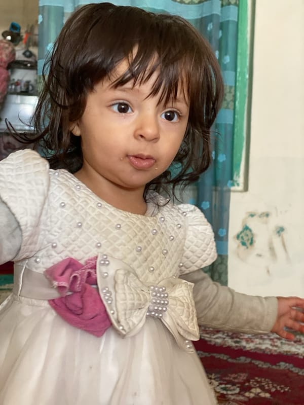 Young girl dances in white dress in Kandahar home