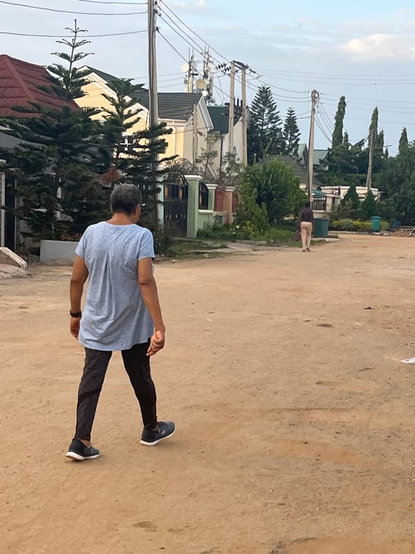 Morning foot traffic through a residential Abuja neighborhood