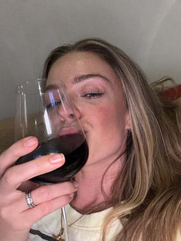 Woman enjoys wine by fireplace with sleeping golden retriever