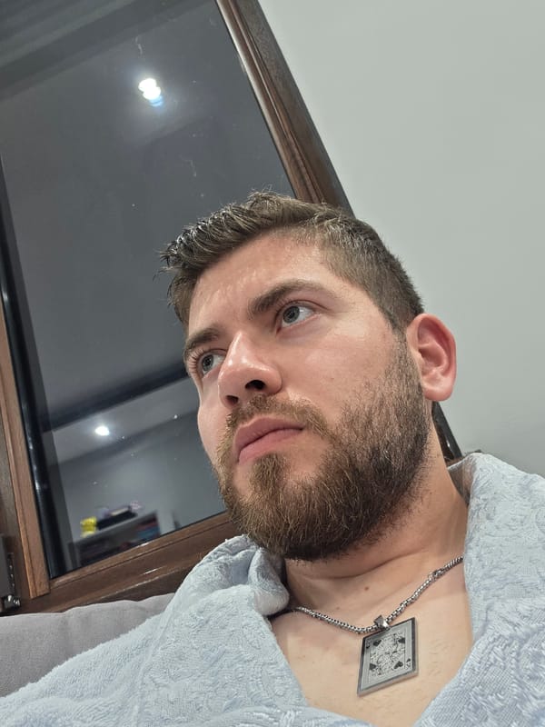 Man photographed in bathrobe with card pendant necklace indoors