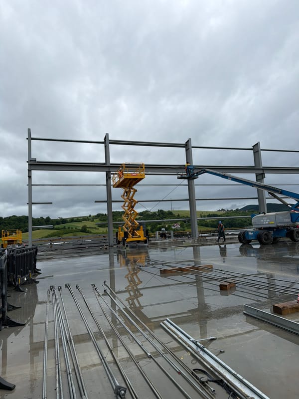 Construction crew works industrial site in cloudy Janowice morning