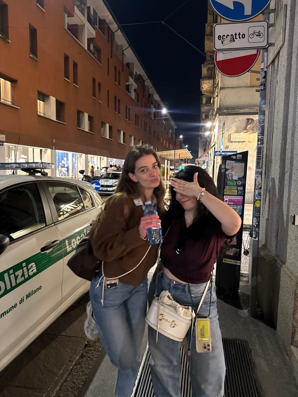 Two women pose on Milan street near police vehicle