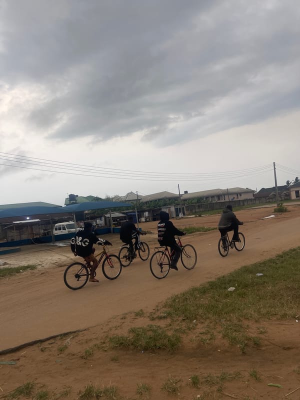 Four cyclists ride dirt road in Abraka, Nigeria