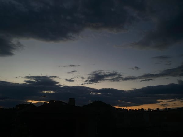 City skyline at dusk under dramatic stormy sunset clouds