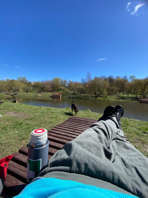 Person relaxes on waterside bench in Moscow morning