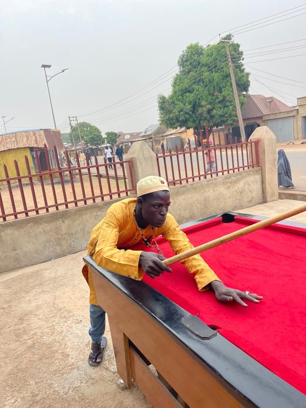 Man plays billiards outdoors in Unguwar Gabas, Nigeria