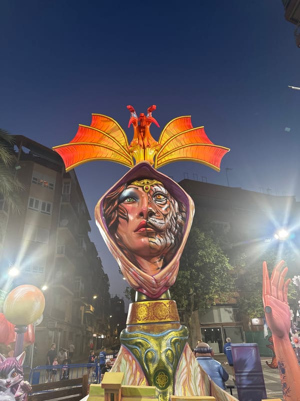 Giant effigy towers over a street scene at dusk