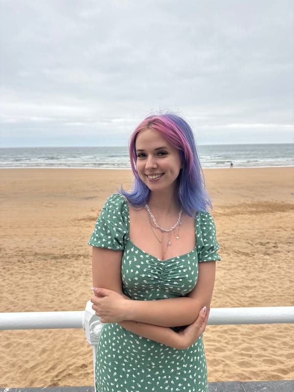Woman poses at Gijón beach promenade under overcast evening sky