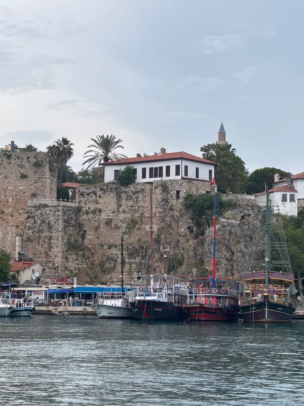 Tourist boat sails past historic Antalya clifftop fortifications