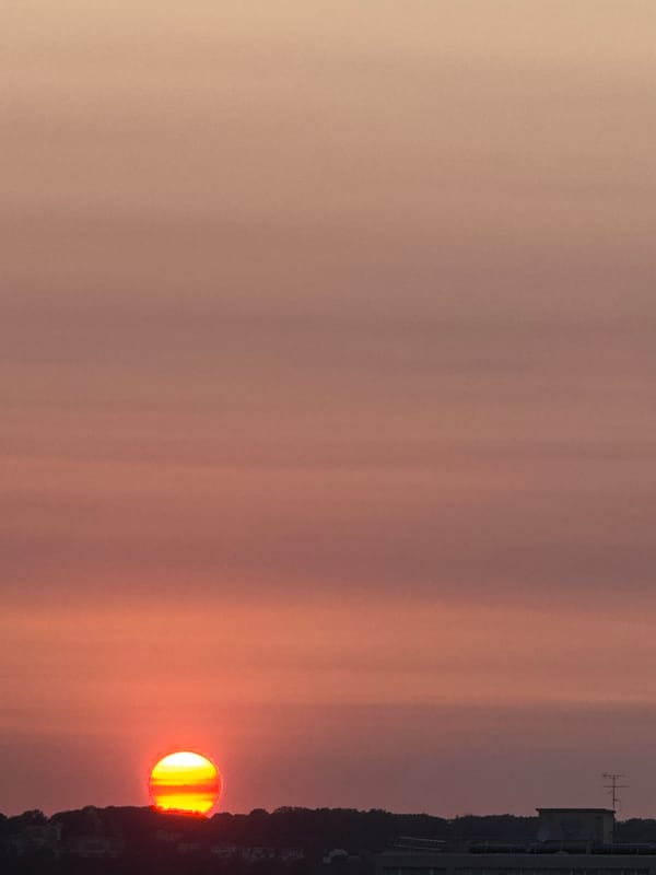 City sunset framed by silhouetted hills and skyline