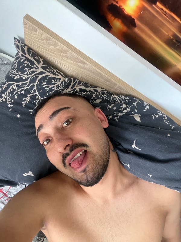 Man makes playful tongue gesture while lying in bed