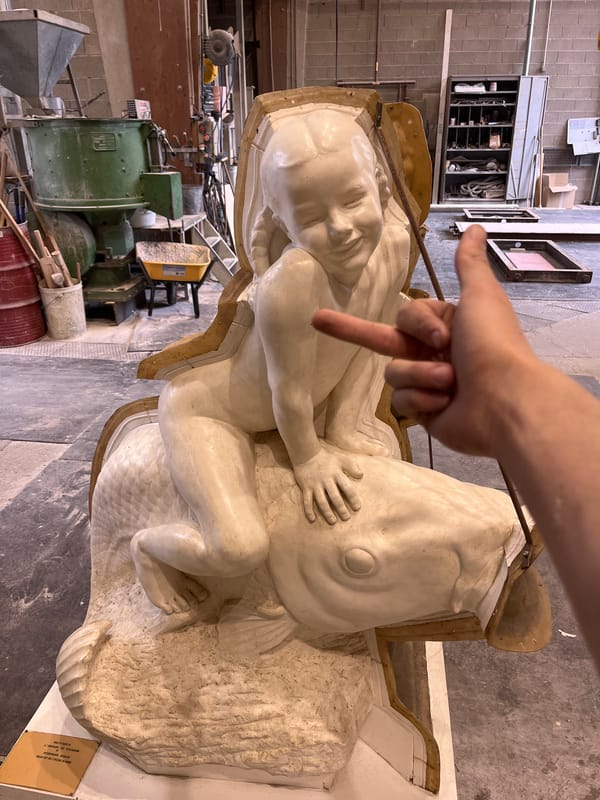 Artist points to human-fish sculpture in French workshop