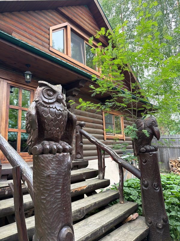 Rustic woodland homestead in Sukhaya, Russia, with carvings and blooms