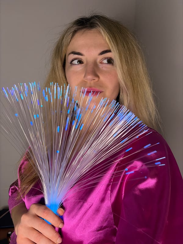 Woman plays with fiber optic lights, cat with toy in Budva