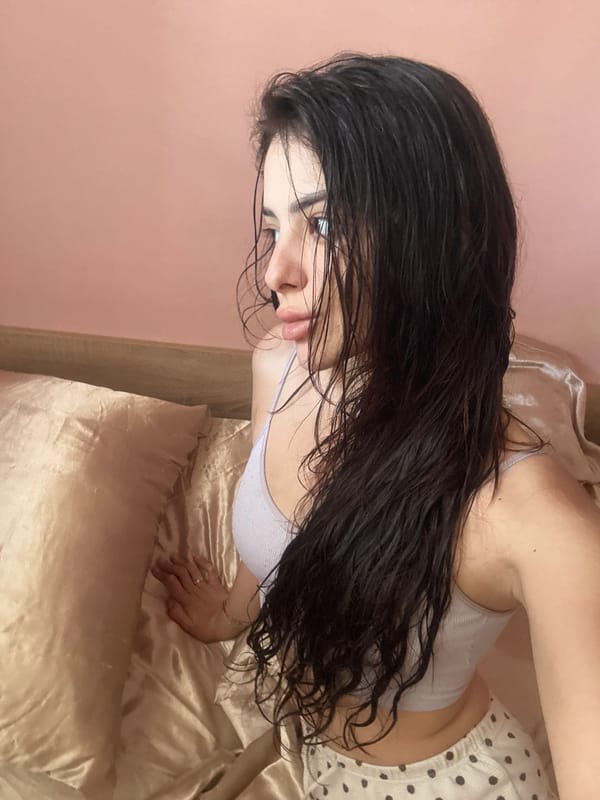 Woman with wet hair rests on bed in Plovdiv