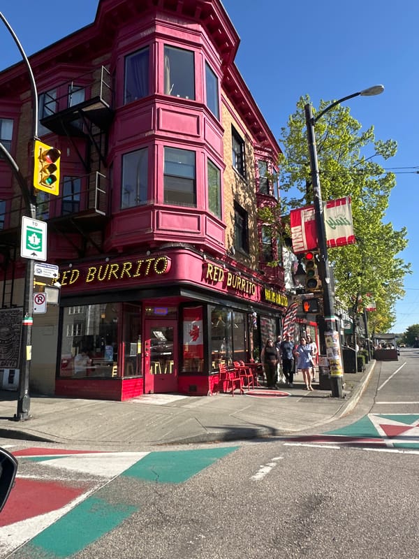 Pedestrian crosses Commercial Drive intersection near Red Burrito restaurant