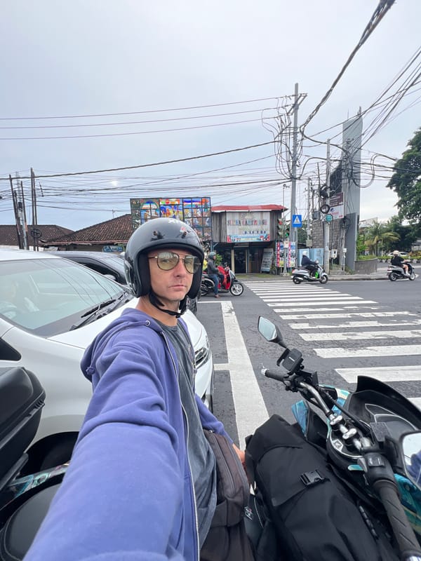 Motorcyclist takes selfie at wet Denpasar crosswalk after rain