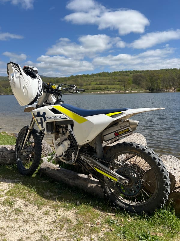 Dirt bike parked by water near tree
