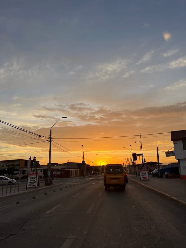 Yellow vehicle drives toward sunset on Arica street