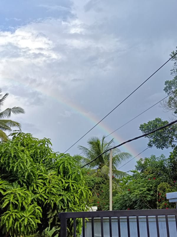 Rainbow appears over cloudy Sumbokrayek amid everyday village activity
