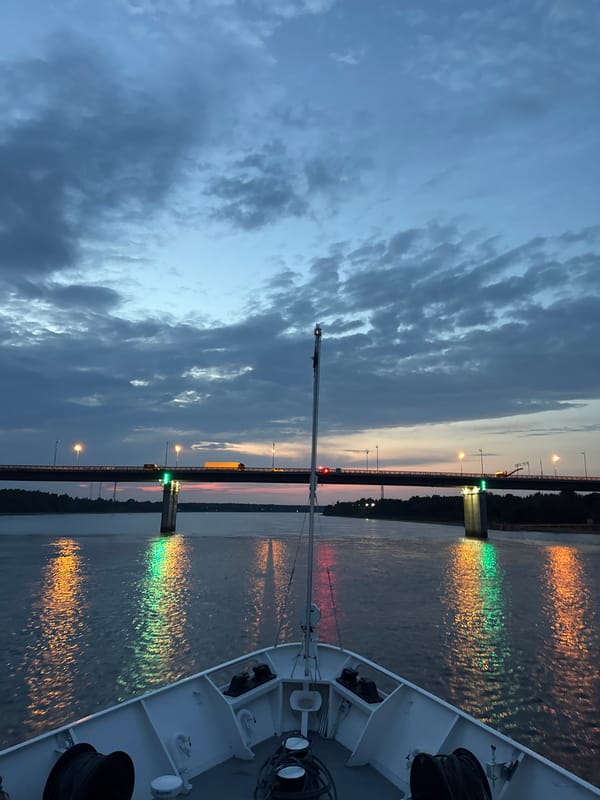 Evening river cruise passing under a lit bridge in Kirovsk