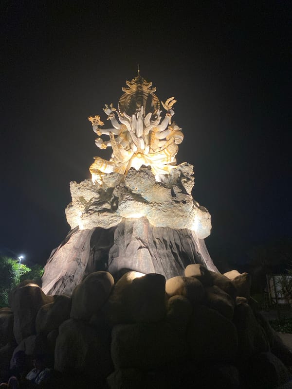 Nighttime visitor captures illuminated Hindu sculptures, lunar halo at Bali park