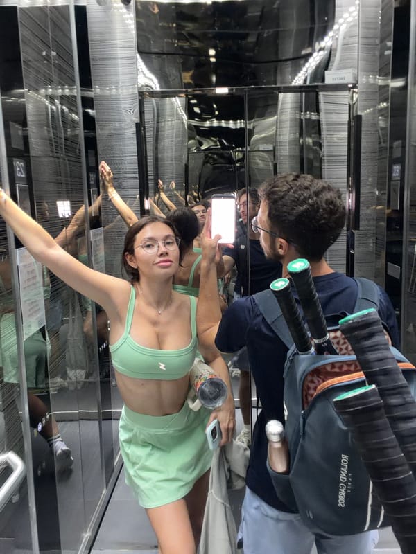 Two people observed in mirrored elevator, man in navy shirt