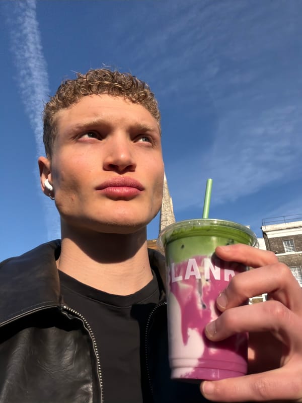 Young man enjoys colorful layered drink in central London
