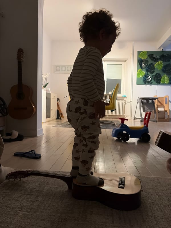 Child plays with guitar in pajamas in Luxembourg home