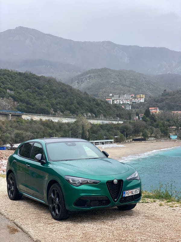 Green Alfa Romeo parked on gravel roadside in Montenegro