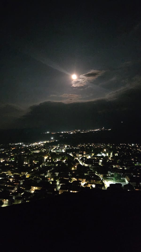 Razlog at night, full moon over a lit city grid