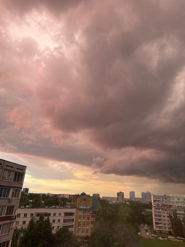 Storm clouds roll over a city skyline at dusk