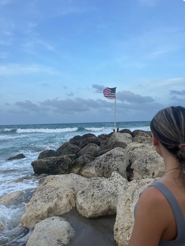 Woman watches ocean waves by flagged rocks in Boca Raton