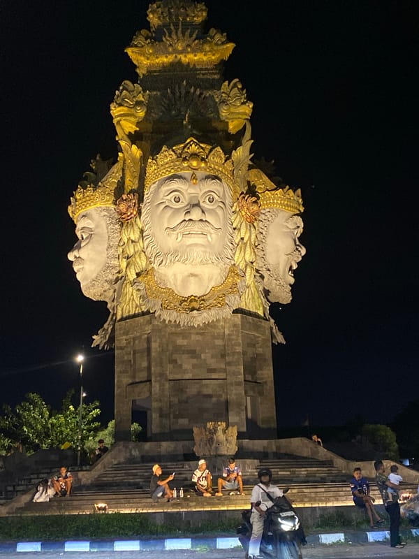 Ornate multi-faced statue illuminated at night in Denpasar