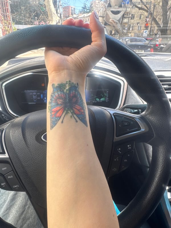 Person with butterfly tattoo photographed in car in Tbilisi
