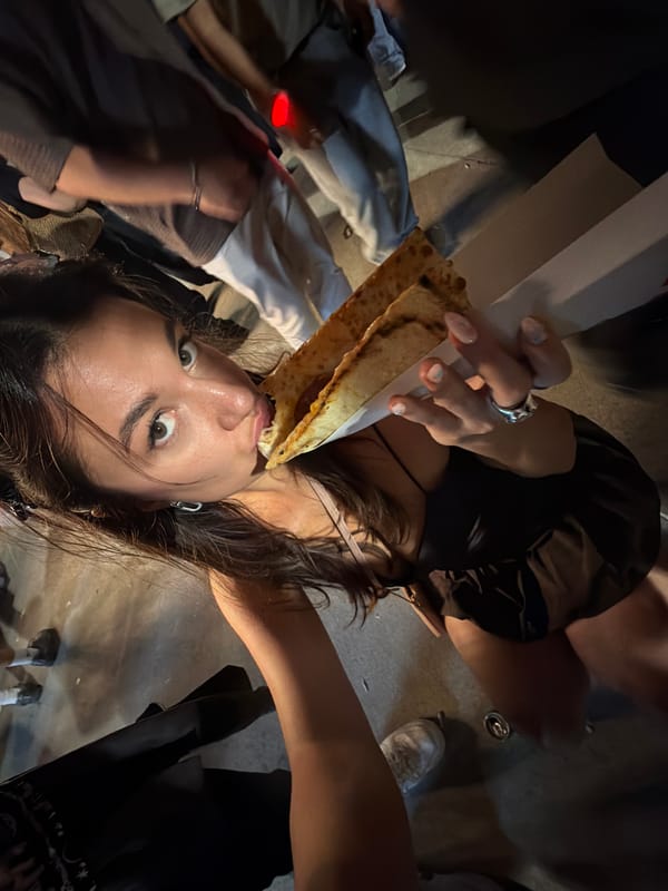 Woman eats pizza on street in Başakşehir at night