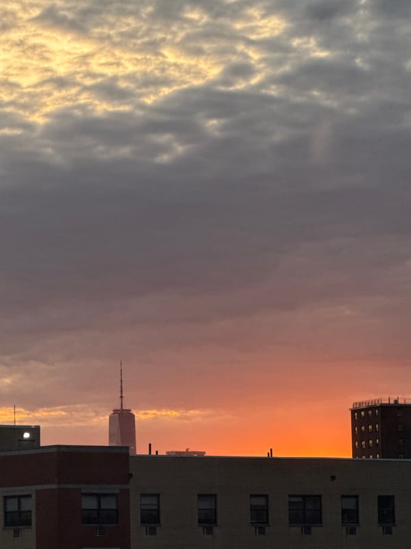 Sunset illuminates New York sky with orange clouds over apartments