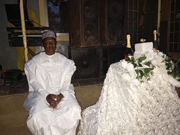 Man in traditional dress observed at table in Nigeria