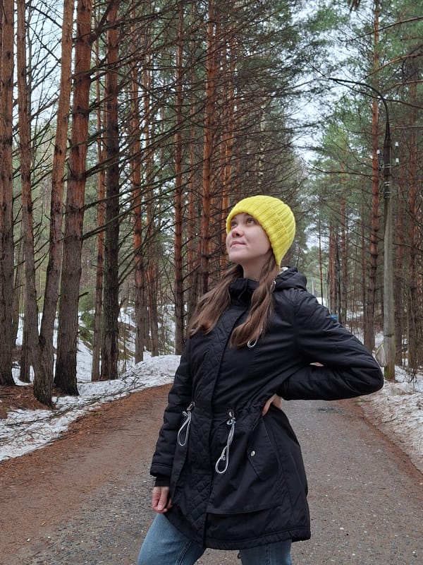 Woman walks forest path amid spring snow in Chaikovsky