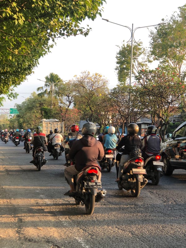 Heavy mixed traffic rolls through Gelam on a regional Indonesian road